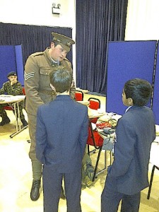 A man in WW1 soldier uniform talks to school children