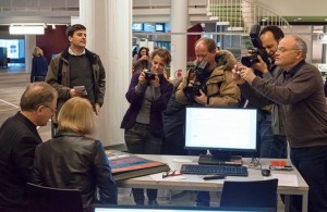 Press cameras surround a contributor describing her collection to a volunteer